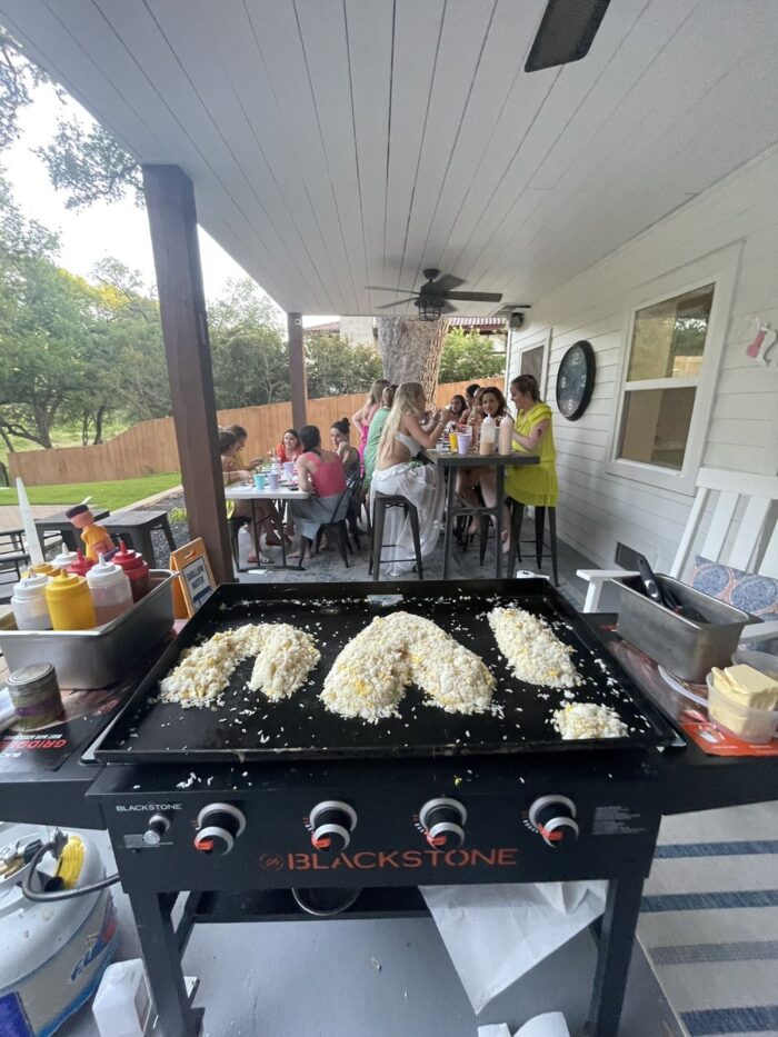 Private hibachi chef's grill under a covered backyard patio with fried rice shaped into a heart and party guests at tables, a setup idea for a Hamilton Halloween hibachi party